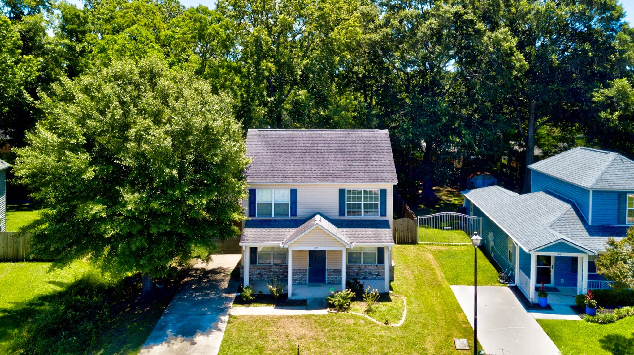 Aerial view of a two-story home and its yard surrounded by mature trees